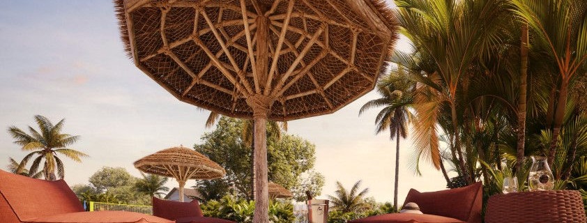 Beach lounge com ombrelones de palha e poltronas na areia